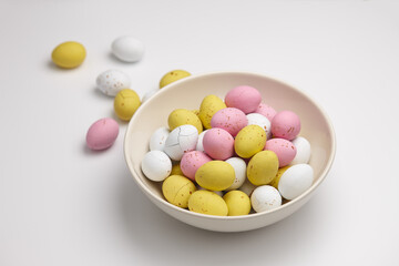 Colorful glazed chocolate candies in plate on white background
