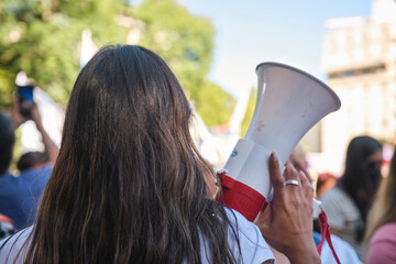 Woman seen from the back holding a megaphone during the feminist strike - obrazy, fototapety, plakaty