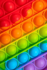 Popular silicone multi-colored anti-stress toy pop it top view close-up. Trendy modern sensory children's toy, fidget push pop it. Texture of colorful bubbles. Abstract background