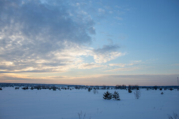 Winter minimalist landscape with colorful clouds in the sky and smoking chimneys on the horizon. winter tourism