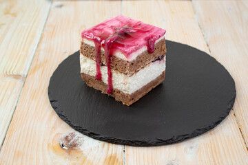 cube cut forest fruit cake, on a black stone tile. Side view 
