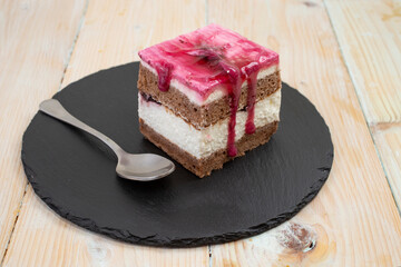 forest fruit cake portion served on a black stone tile. Side view 