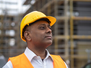 Profile portrait of a serious civil engineer or factory worker wearing a safety helmet and looking aside