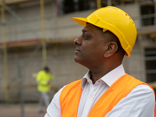 Profile portrait of a serious civil engineer or factory worker wearing a safety helmet and looking aside