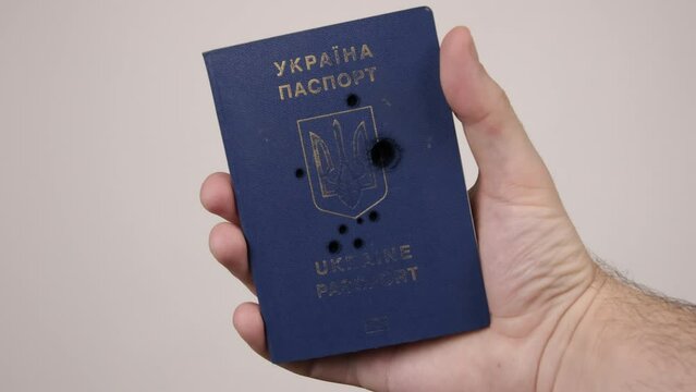 War between Russia and Ukraine. The concept of murder, occupation, aggression. Male hand holds a blue passport of Ukraine.