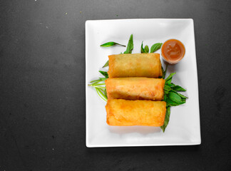 Fried Chinese traditional spring roll food on ceramic plate (beautiful shape) on black background