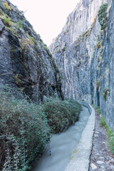 Vertical photo of a water-filled irrigation ditch between mountain walls on the route of the...