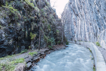 Large water-filled channel between mountain walls on the route of the Monachil river, in Los...