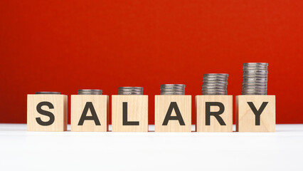 salary word made with wooden blocks with stacked coins. growing trend. red background. Investment growth concept