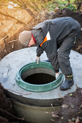 A worker installs a manhole on a septic tank. Conducting communications in a residential building
