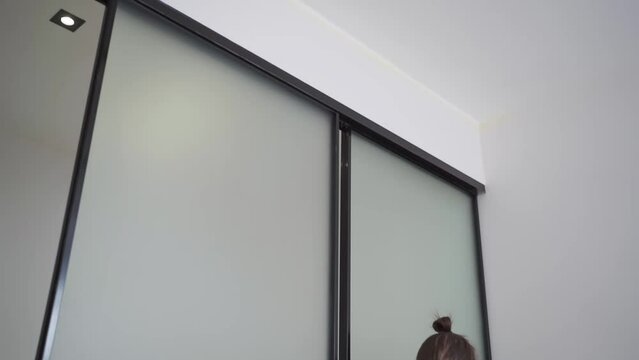 master adjusts sliding doors of wardrobe made of metal and glass.
