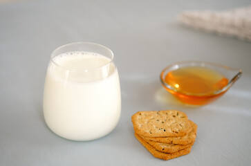 Glass of milk, honey and whole wheat cookies on the table.