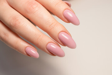 Nude manicure. Gel nail polish in light pink color. Almond shaped nails. Beautiful manicure.  - obrazy, fototapety, plakaty