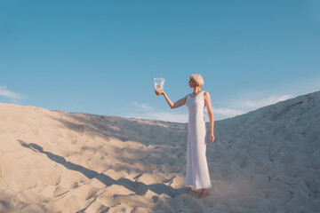 blonde woman in the desert with goldfish in her hands	