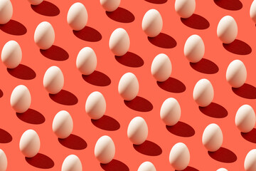 Pattern made of white eggs and sharp shadow on pastel red background. Minimal food concept.