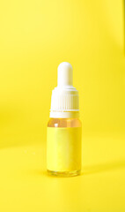Yellow serum or essential oil glass dropper bottle on yellow background. Organic skin care cosmetics. Health care, spa and beauty concept. Product Mockups