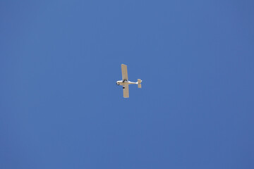 Mały biały samolot na tle niebieskiego nieba latem. 