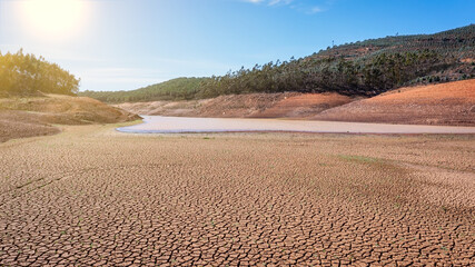 Landscape of low water and dry land in advance, severe drought in the reservoir of Portugal. Ecological disaster, soil dehydration. desert, drought, - obrazy, fototapety, plakaty