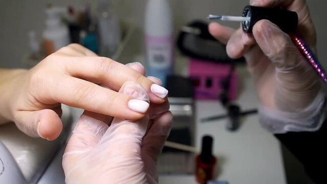 manicure and pedicure master apply white nail polish with a black brush