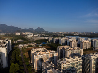 Aerial view of Jacarépagua in Rio de Janeiro, Brazil. Residential buildings and mountains in the background. Rio 2 and Cidade Jardim. Sunny day. Sunset. Drone take.