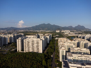 Obraz premium Aerial view of Jacarépagua in Rio de Janeiro, Brazil. Residential buildings and mountains around the lake. Barra da Tijuca beach in the background. Sunny day. Drone photo