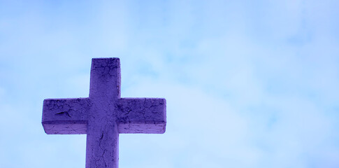 Blue stone cross on light blue sky background