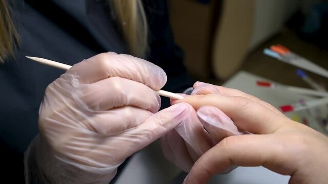 the manicure master protects the nail before the procedure with a wooden stick