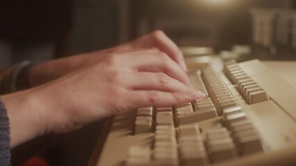 Hands typing on the keyboard of an old  micro computer. Close-up.