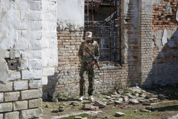 Soldiers shoot at a target with automatic weapons outdoor at ruined village.