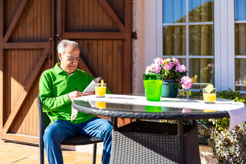 Elderly man drinking a lemon soda on the porch of his home on a spring day.