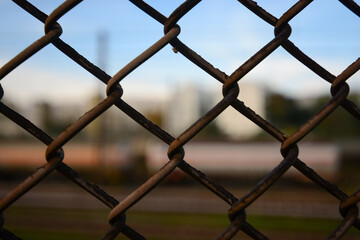 Fototapeta premium close-up of ice rusty fences with blurred background in which a train can be guessed