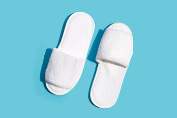 Hotel slippers on blue background. Copy space