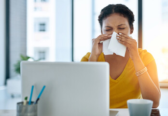 Her immune system could use a boost. Shot of a young designer blowing her nose in an office.