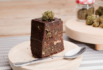 Chocolate cupcake muffins with cannabis buds. Marijuana hemp medical drugs in food dessert. Chocolate herb muffins cooking. Marijuana cake on a brown wooden table.