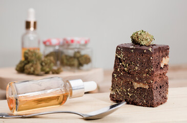 dropper bottle glass marijuana oil drops and chocolate cupcake muffins with cannabis buds.Marijuana...