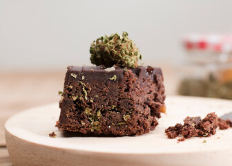 Chocolate cupcake muffins with cannabis buds. Marijuana hemp medical drugs in food dessert. Chocolate herb muffins cooking. Marijuana cake on a brown wooden table.