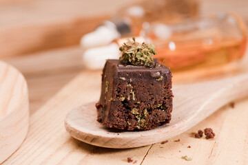 Chocolate cupcake muffins with cannabis buds in wooden spoon, oil pot and cooking jars. Marijuana hemp in food dessert. Chocolate herb muffins cooking. Marijuana cake on a brown wooden table.