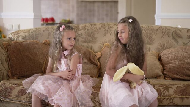 Argued sisters making pinky swear shaking little fingers hugging in slow motion. Caucasian girls making peace after fight in living room at home indoors. Slow motion