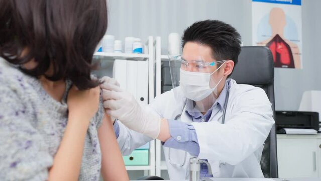 Asian male doctor wear mask, give treatment to young woman in hospital