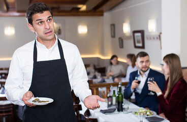 Portrait of waiter dissatisfied with small tip from restaurant visitors