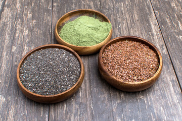 flax seeds, supergreens powder and Chia seeds in a wooden bowls. Healthy food concept.