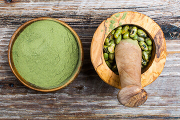 supergreens powder and green bean in a mortar with a whisk on a wooden background Healthy eating concept.