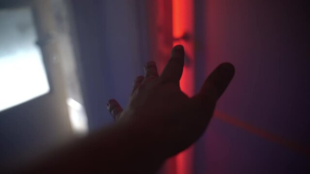 Concept of opening door to the hell, hand of murderer approaching to the room door and slowly opening, horrible scene of room with red lighting, fog and obscure chaos and garbage. Scary crime in dark