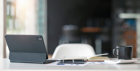 Contemporary workspace with tablet computer and supplies on wooden table, dark tone color. Rear view of tablet.