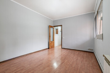 Empty room with wooden parquet, aluminum windows, gray painted walls and mahogany colored carpentry...