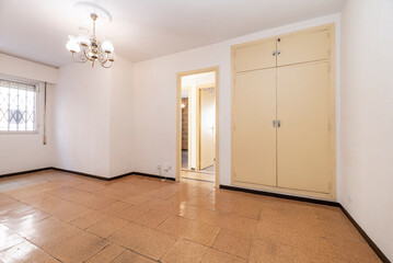 Empty room with cork tile flooring and cream painted wooden cabinet doors and bay window in the background