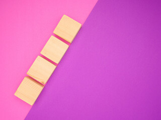 Top view of blank four wooden cubes on a purple and pink background