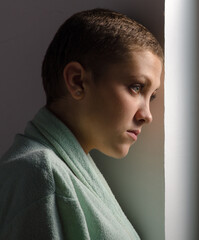 Fototapeta premium Young cancer patient standing in front of hospital window