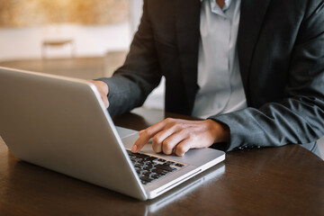 Man hands is typing on a laptop and holding tablet .