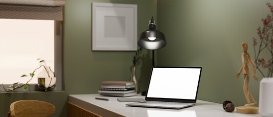 Modern stylish workplace interior with portable notebook laptop against green wall.